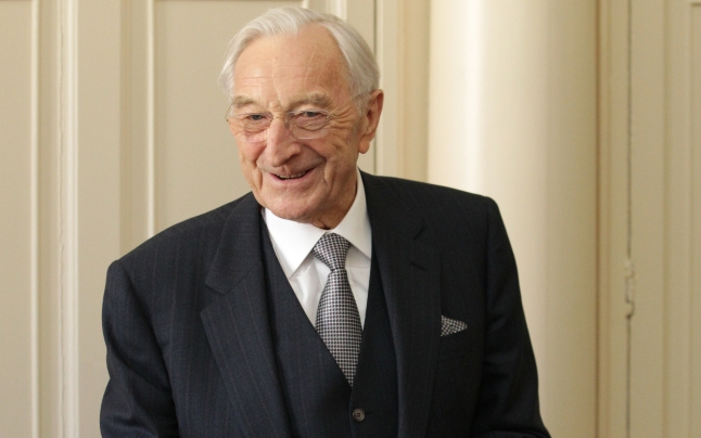 Martin Naughton wearing dashing suit, smiling and speaking at podium at Trinity College Dublin.